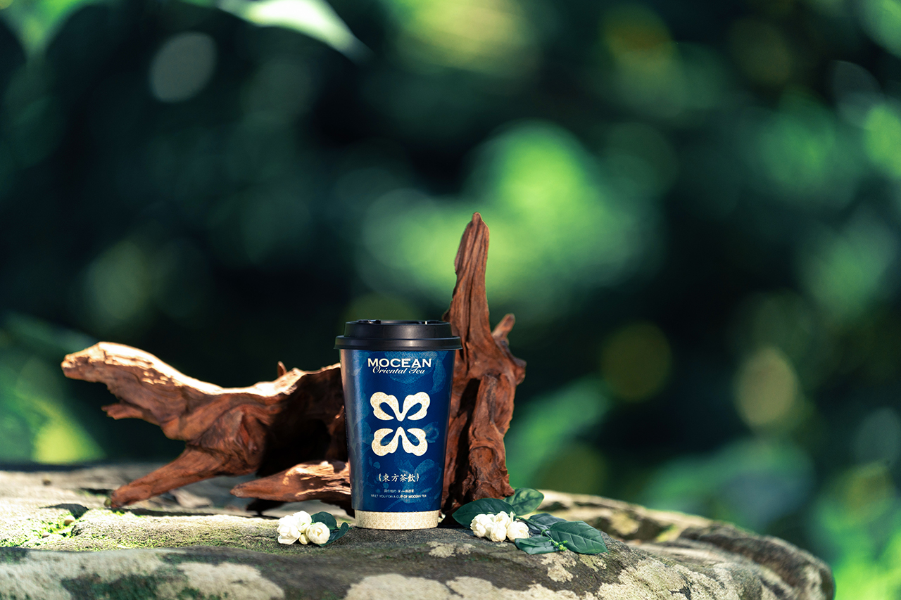 A Mocean cup resting on driftwood among jasmine blossoms in a sunlit forest